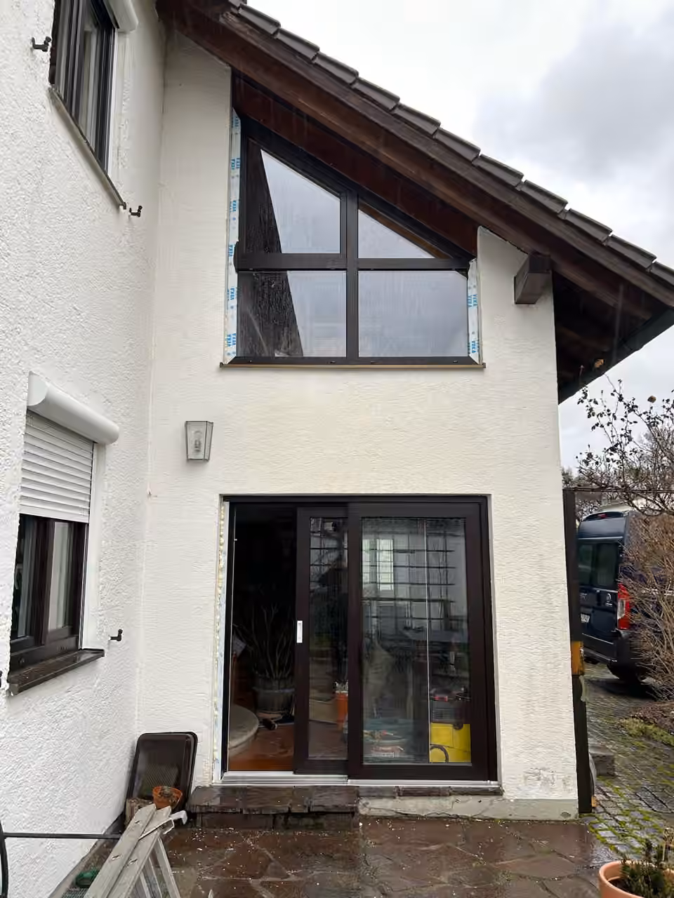 Hausgiebel mit dunklen Fenstern und einer Terrassentür