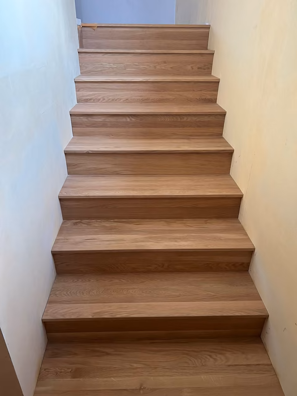 Gerade Treppe, vollständig mit Eichenholz verkleidet, zwischen zwei hellen Wänden