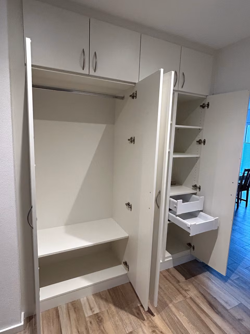 Geöffneter weißer Einbauschrank mit Garderobenfach, Regalböden und Auszügen