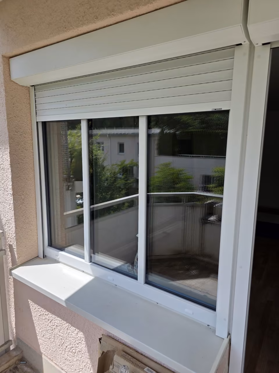 Weißes Fenster mit Rollladen und neuer Fensterbank