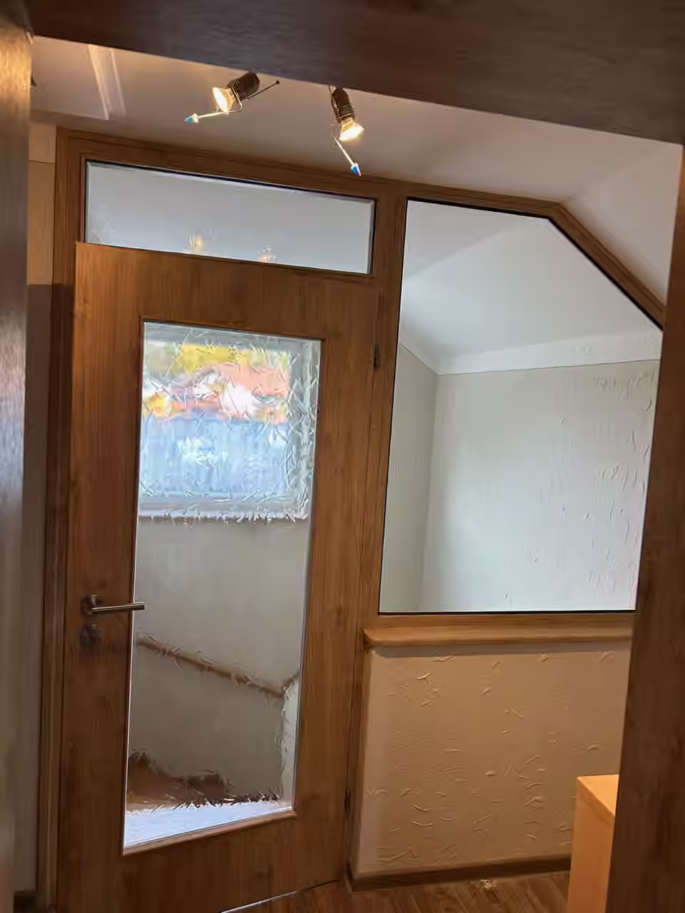 Holztür mit Glasausschnitt und verglastem Oberlicht in einem Dachgeschoss-Flur