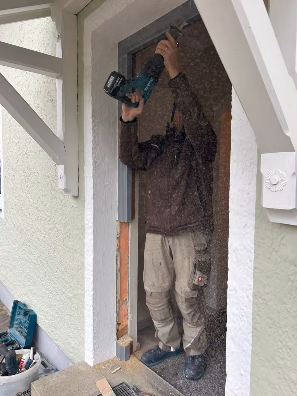 Mitarbeiter bohrt beim Einbau einer Haustür am Rahmen über Kopf