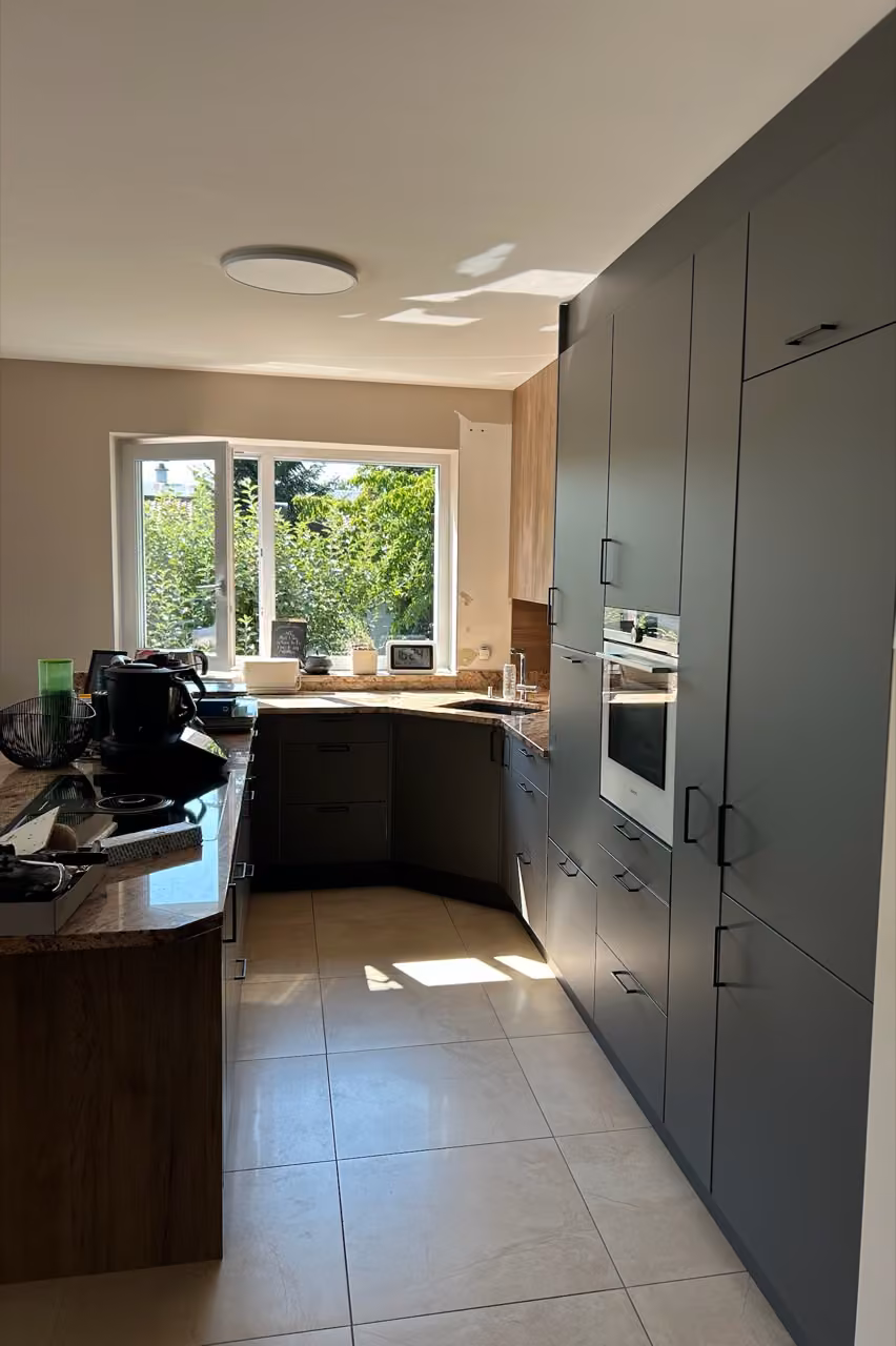 Dieselbe Küche aus einem anderen Blickwinkel, mit Fensterfront und geschwungener Theke