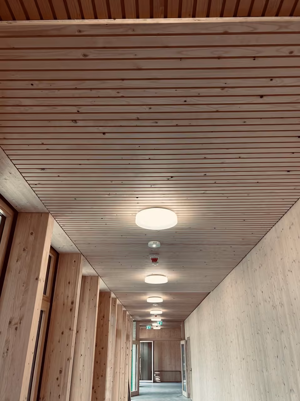 Flur mit Holzlattendecke und Holzwänden in einem Neubau