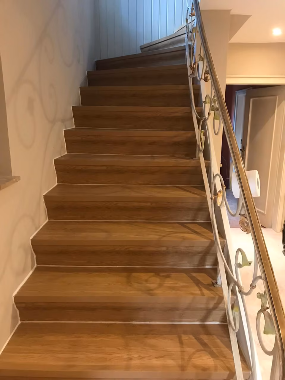 Treppe mit Eichenstufen und geschwungenem Schmiedeeisengeländer