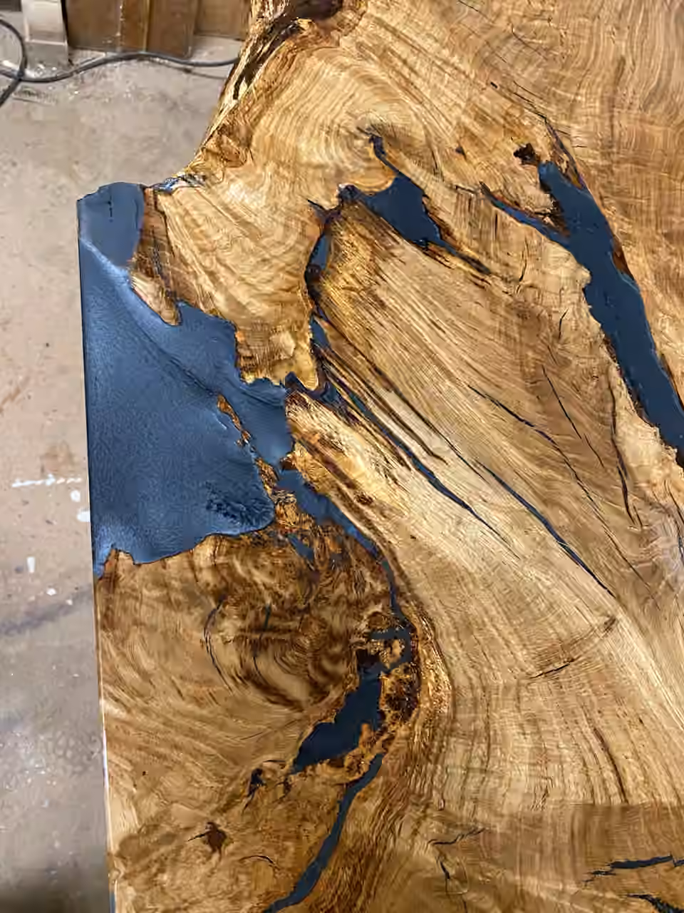 Nahaufnahme einer Tischplatte, Astlöcher mit blauem Epoxidharz ausgegossen